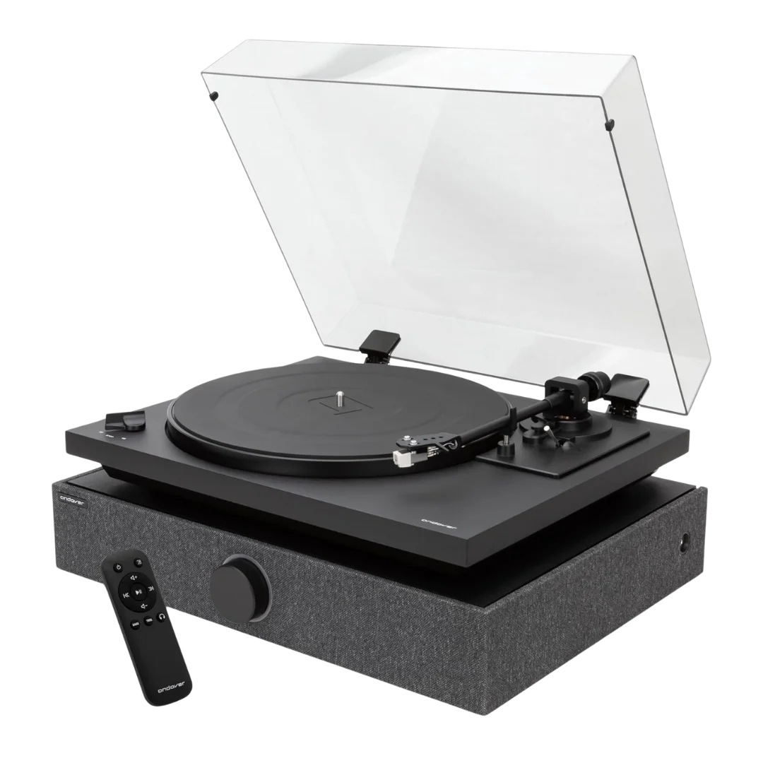 Andover SpinDuo record player with speakers with its clear dust cover open, sitting atop a grey fabric-wrapped speaker base, shown alongside its slim black remote control.