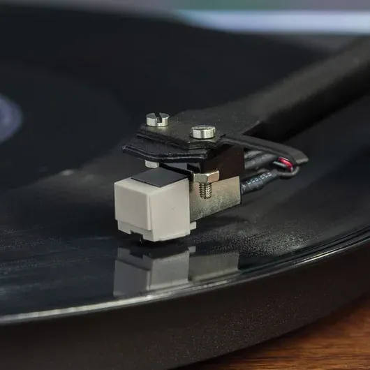 Close-up of a Crosley record player NP-5 needle on a vinyl record, showing the stylus in play position.