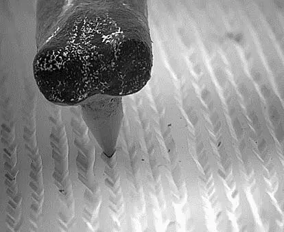 Close-up microscopic view of a record player’s stylus tracing the grooves of a vinyl record, showcasing the intricate interaction between the needle and the record surface