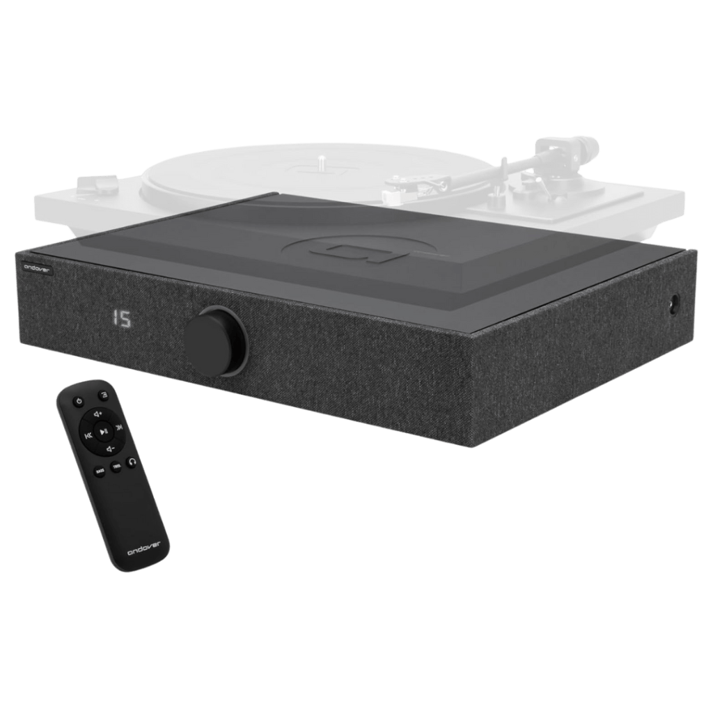 Andover Spinbase 2 wireless turntable speaker system in black, shown with a matching remote control and a blurred turntable in the background.