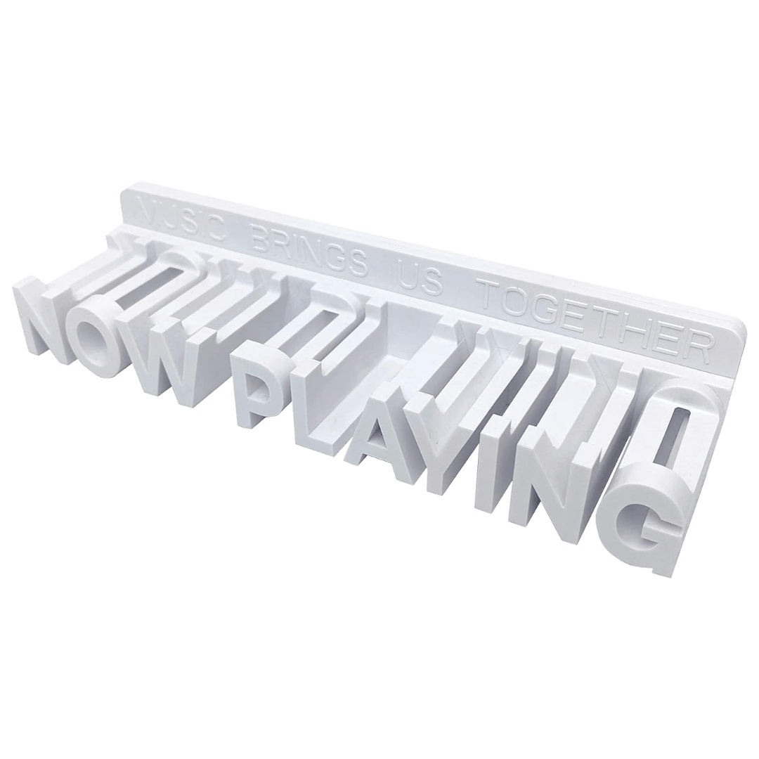 White 3D-printed “Now Playing” vinyl record stand with bold block letters and slots for holding record sleeves, featuring the phrase “Music Brings Us Together” engraved along the top edge.