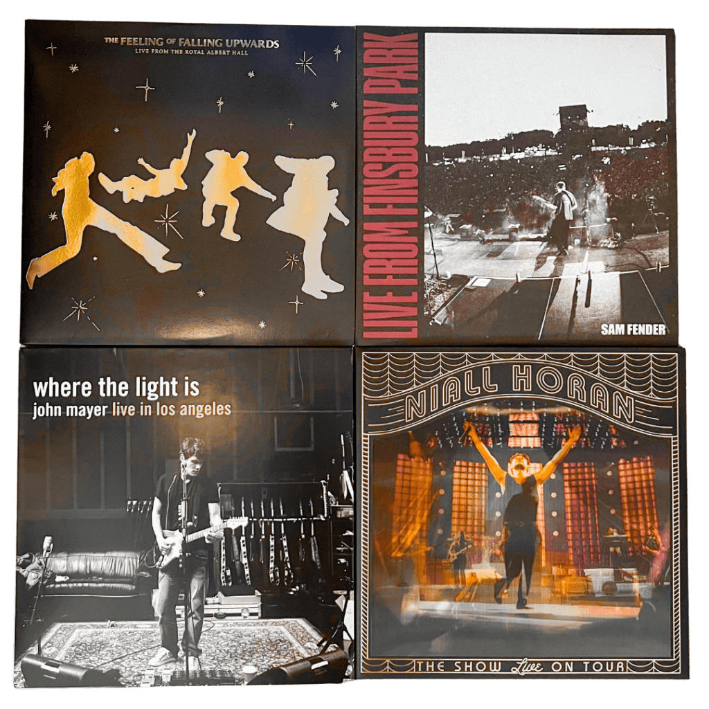 Four vinyl record covers: The Feeling of Falling Upwards by The 1975 (live at Royal Albert Hall) with golden silhouettes on a dark starry background, Sam Fender’s Live from Finsbury Park with a black-and-white photo of Fender on stage, John Mayer’s Where the Light Is (live in Los Angeles) showing Mayer with his guitar in a studio setting, and Niall Horan’s The Show Live on Tour featuring Horan mid-performance on a glowing stage.