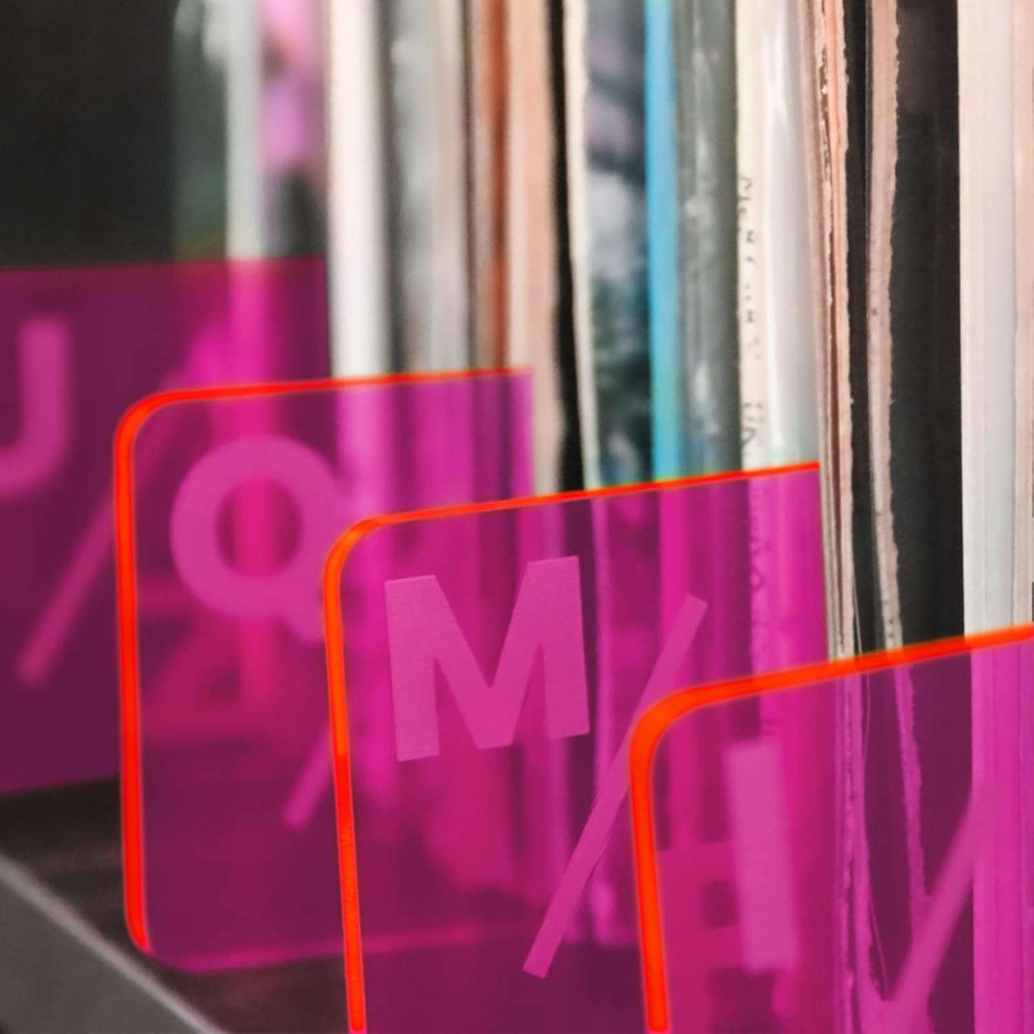 Pink TAKMORK acrylic record dividers with etched letters for organizing vinyl collections alphabetically.