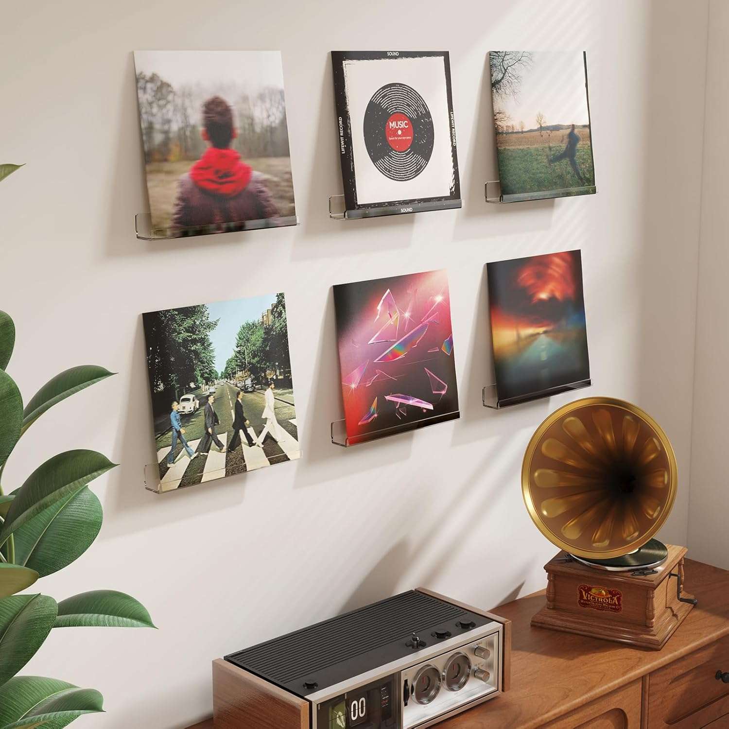 Modern vinyl listening setup with six floating record display shelves holding album covers, including The Beatles’ Abbey Road, a blurred portrait cover, abstract geometric artwork, and a few minimalist designs. Below the display, a vintage-style Victrola record player with a gold horn sits on a wooden cabinet, alongside a retro receiver.
