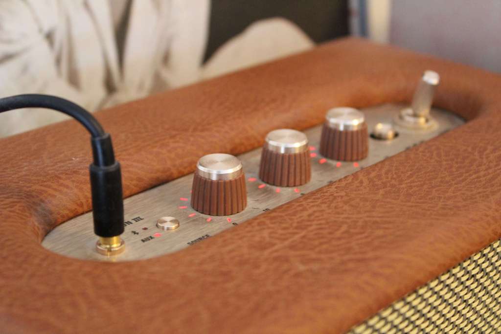 Close-up of the top control knobs on a Marshall speaker in a brown leather finish, showing lit red indicator lights.