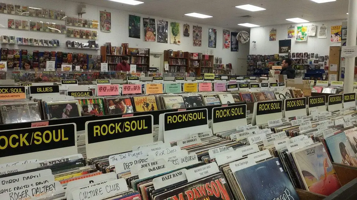 Interior of The Great Escape record store with aisles of vinyl and signs for genres like rock, soul, reggae, and hip hop, with walls lined with posters.