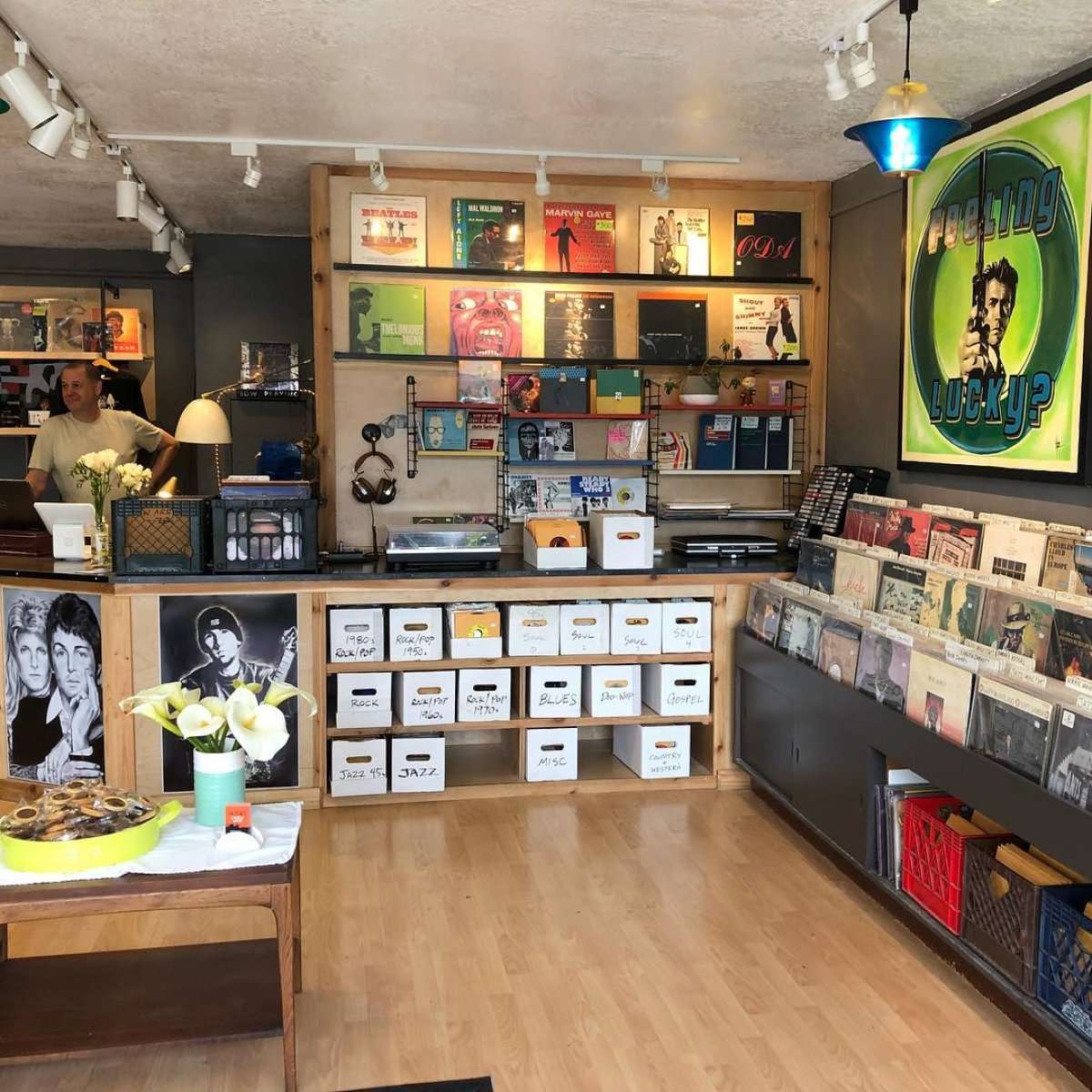 ozy Berkeley record store interior with wall of LPs, genre crates, and “Feeling Lucky?” poster.
