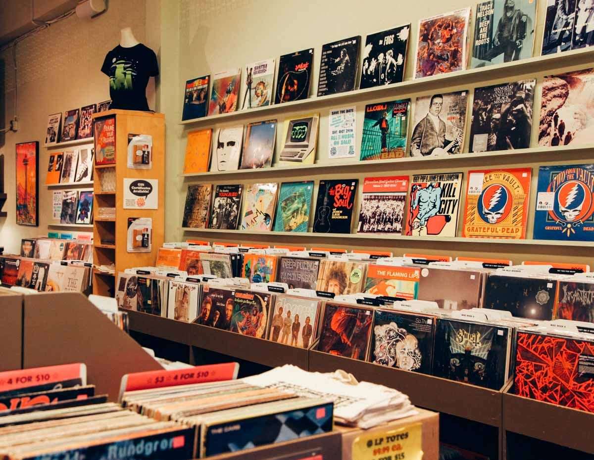 Warm, well-lit LP bins with a wall shelf of featured album covers and bargain dividers at Jive Time Records.