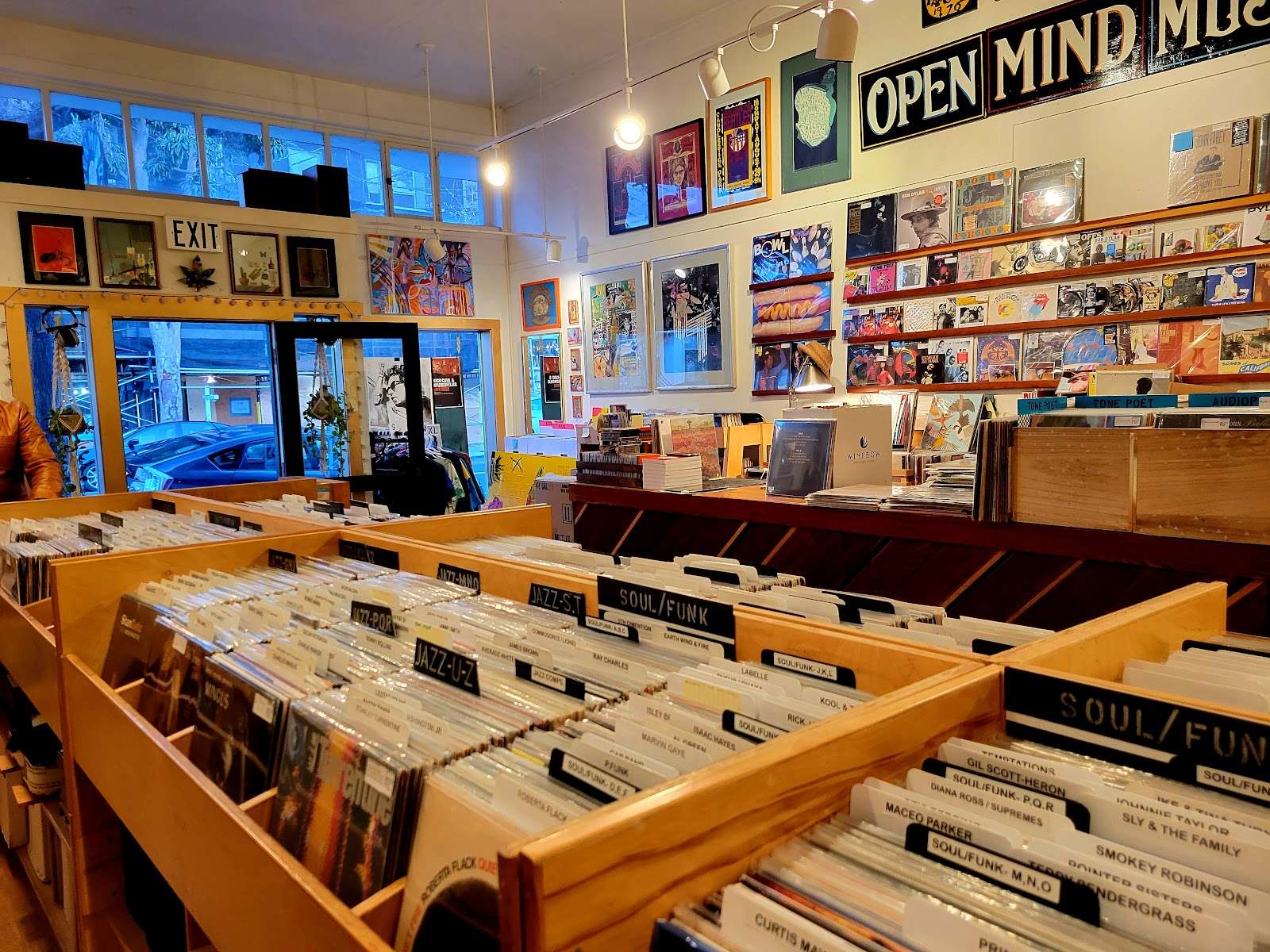 warm East Bay shop interior with wooden bins labeled Soul/Funk and Jazz and featured albums on wall.