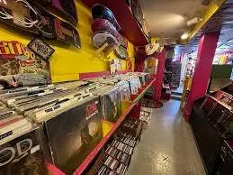 Narrow, colorful aisle—magenta and yellow shelves lined floor-to-ceiling with punk LPs and tapes.