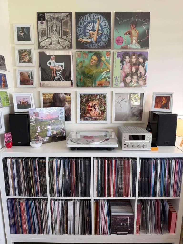 Nine-cover vinyl wall above a white Audio-Technica AT-LP70X and Sony micro hi-fi; “The Pyre” LP displayed on a stand.