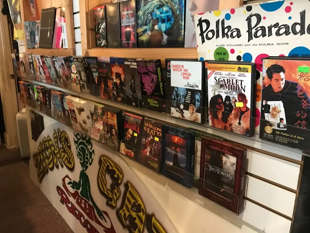 Counter and wall display packed with cult DVDs and vinyl sleeves inside Zion’s Gate, with hand-painted shop graphics.