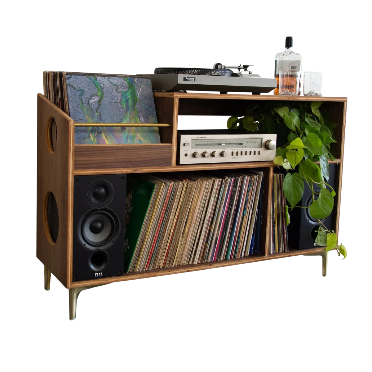 Mid-century style walnut record console with brass legs, holding a turntable on top, a silver stereo receiver and trailing green plant in the middle, bookshelf speakers on each side, and shelves packed with vinyl records